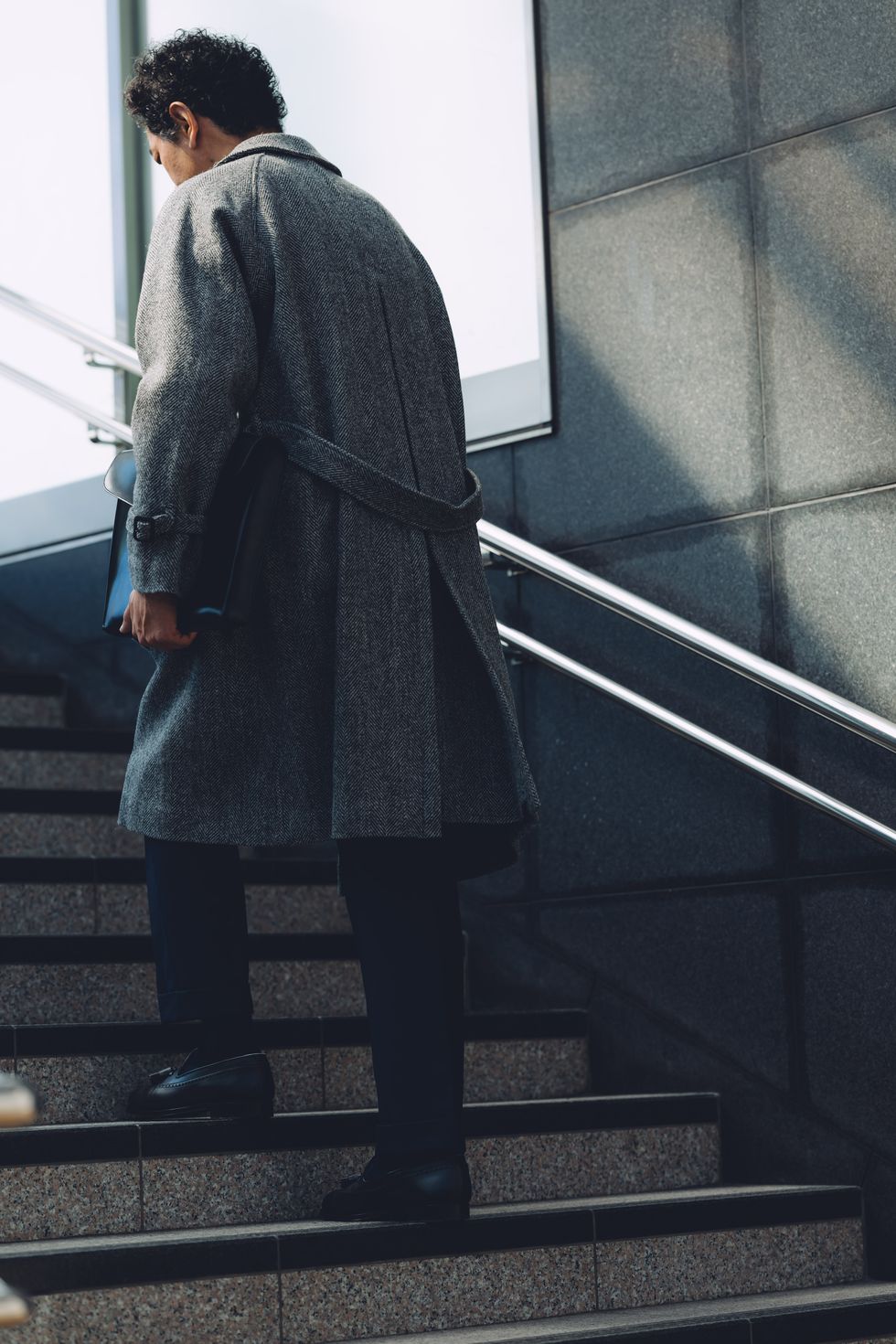 a person in a coat walking up stairs
