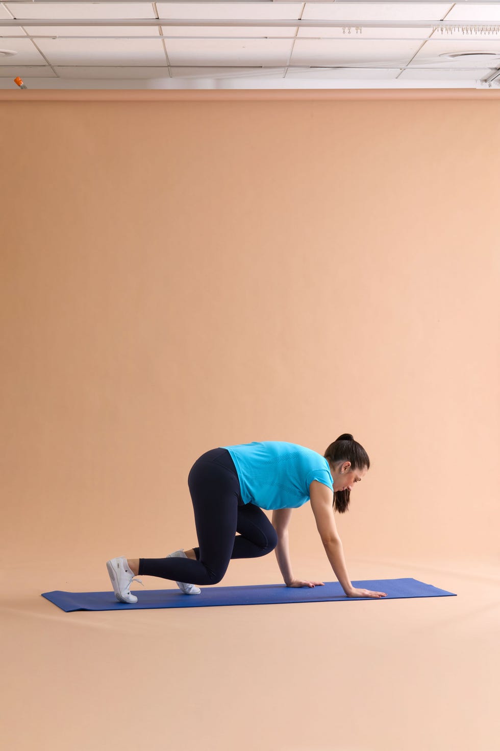 A person in an athletic pose on an exercise mat demonstrating a fitness position