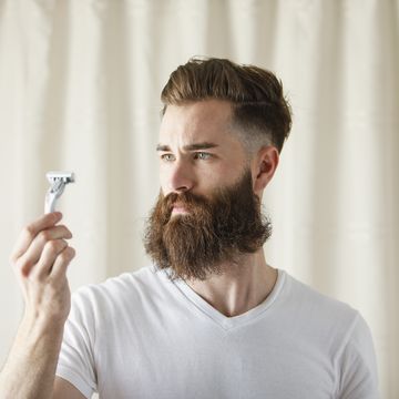 bearded caucasian man examining razor