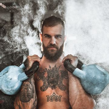bearded male working out with kettlebells in gym