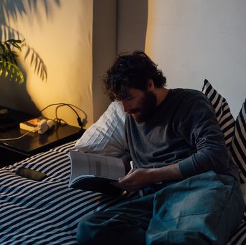 man reading book in bed