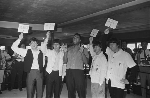 The Beatles holding up cards describing Clay as: 'Greatest', '218 lbs', 6', 3''' and '22 yrs'.