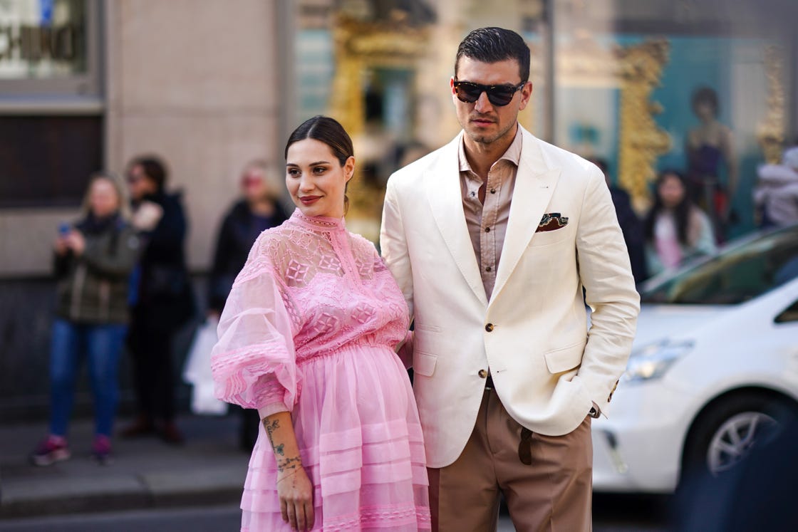 a pregnant woman in a pink dress next to a man in a cream blazer and light brown button down shirt in a roundup of the best gifts for new dads 2024 