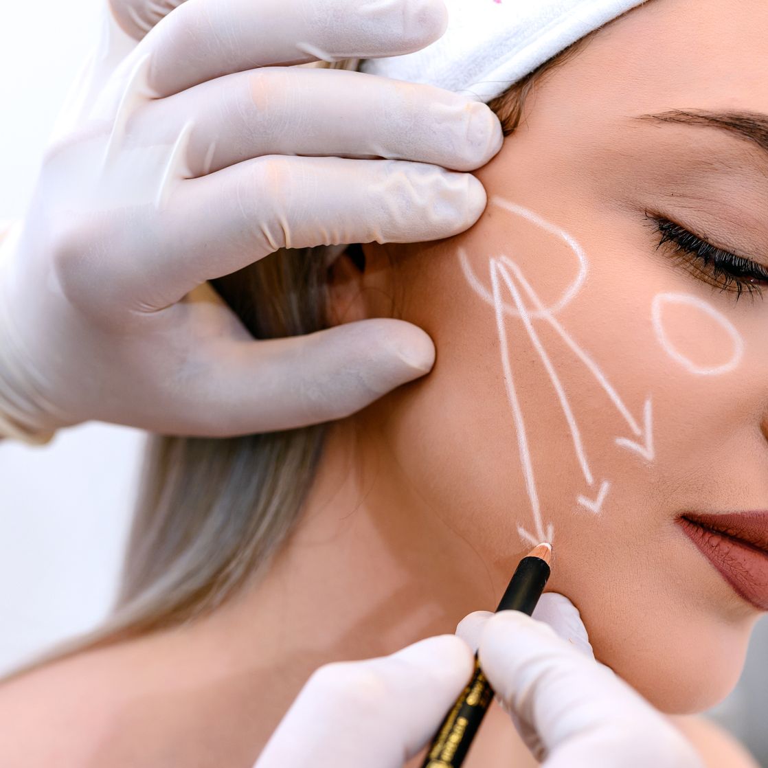 beautician draw correction lines on woman face