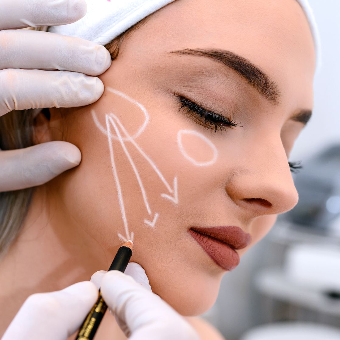 beautician draw correction lines on woman face