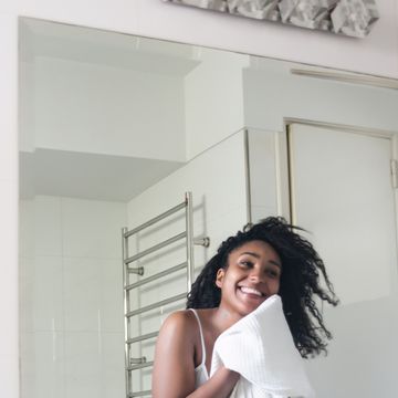 beautiful black woman drying her face with a towel while looking at herself in the mirror smiling