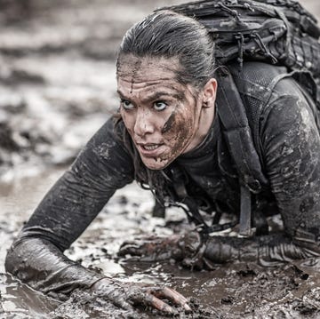 Beautiful brunette female military swat security anti terror agent crawling during operations in muddy sand
