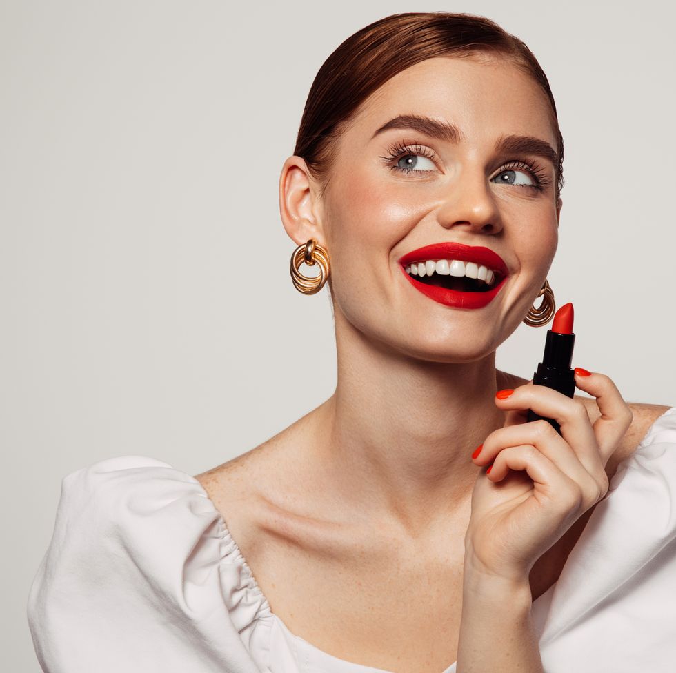 woman with bright make up applying red lipstick