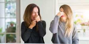 Beautiful family of mother and daughter together at home smelling something stinky and disgusting, intolerable smell, holding breath with fingers on nose. Bad smells concept.