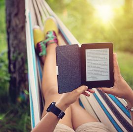 beautiful girl is reading e book in the hammock