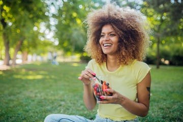 beautiful girl resting on the grass and eating fruit salad