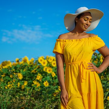 easter outfit ideas, woman standing in flower field wearing a white hat and sundress