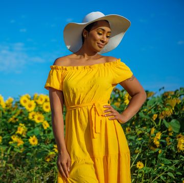 easter outfit ideas, woman standing in flower field wearing a white hat and sundress