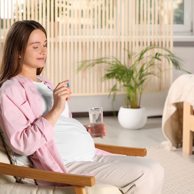 beautiful pregnant woman taking pill at home