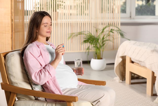 beautiful pregnant woman taking pill at home