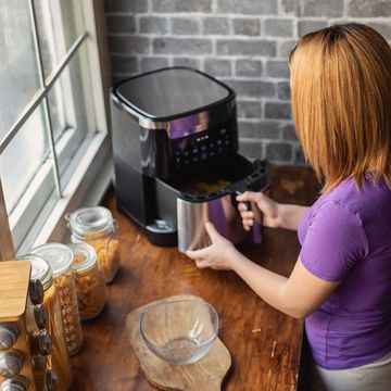 mujer pelirroja en una cocina utilizando una freidora de aire
