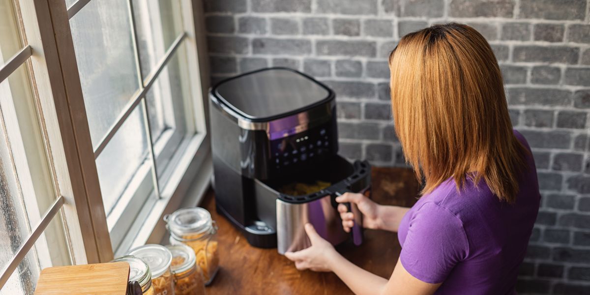 mujer pelirroja en una cocina utilizando una freidora de aire