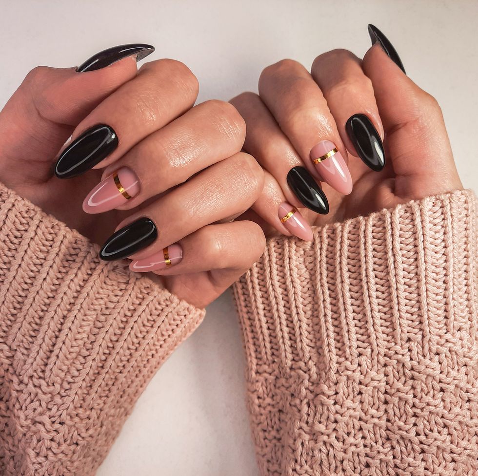 beautiful two tone manicure with gold design hands in a sweater with black and camouflage gel polish stylish nail polish coating