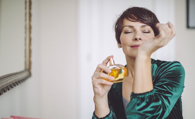 mujer poniendose perfume en un brazo