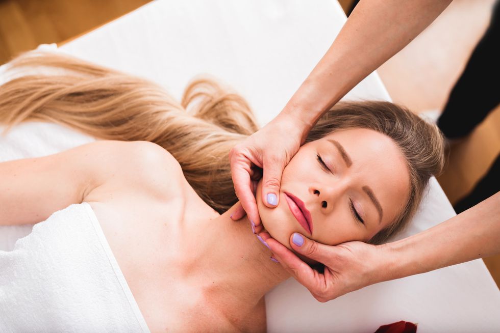 beautiful woman doing facial massage in a spa salon