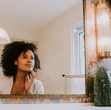 a beautiful woman examines her skin in a bathroom mirror