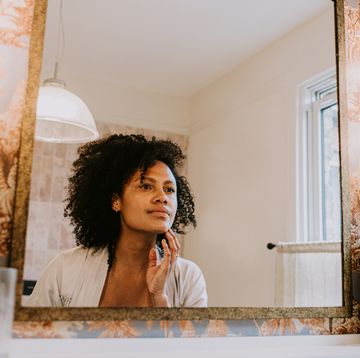 a beautiful woman examines her skin in a bathroom mirror