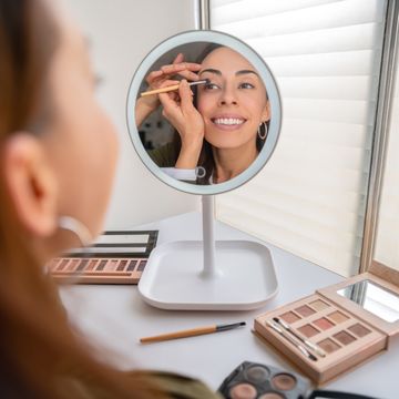 beautiful woman putting make up on at home using a mirror