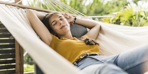 beautiful woman with arms raised napping on hammock in yard