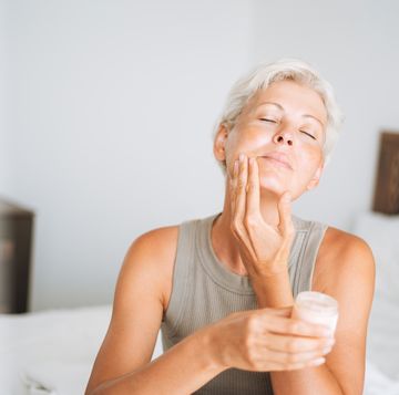 beautiful woman with short hair applies cream to her face at home, morning skincare routine