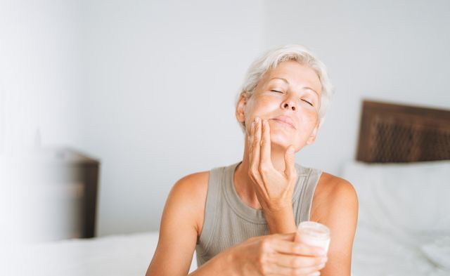 beautiful woman with short hair applies cream to her face at home, morning skincare routine