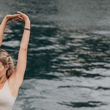 beautiful young adult woman practicing yoga near the river