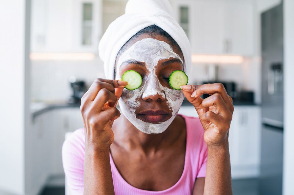 beautiful young afro woman with cucumber on eyes