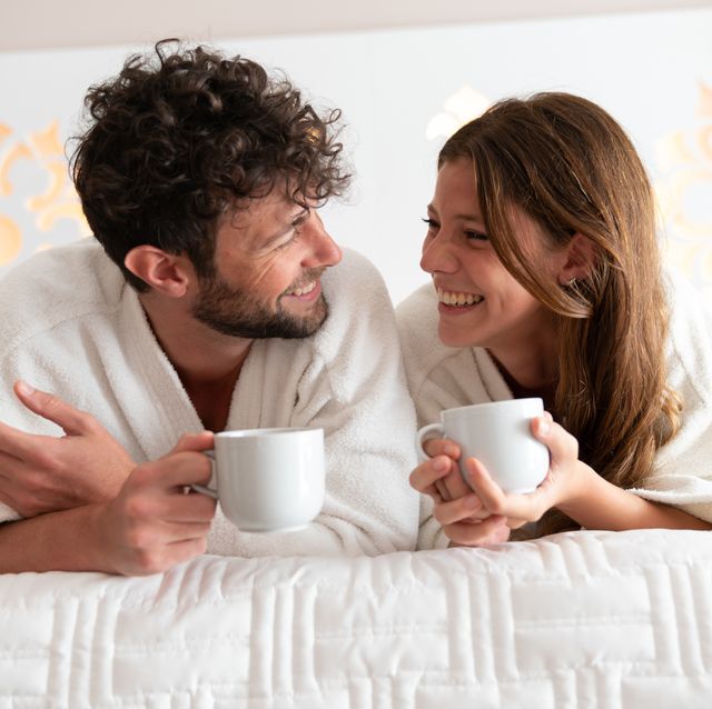 beautiful young couple at home relaxing on bed wearing bathrobes and drinking a cup of coffee