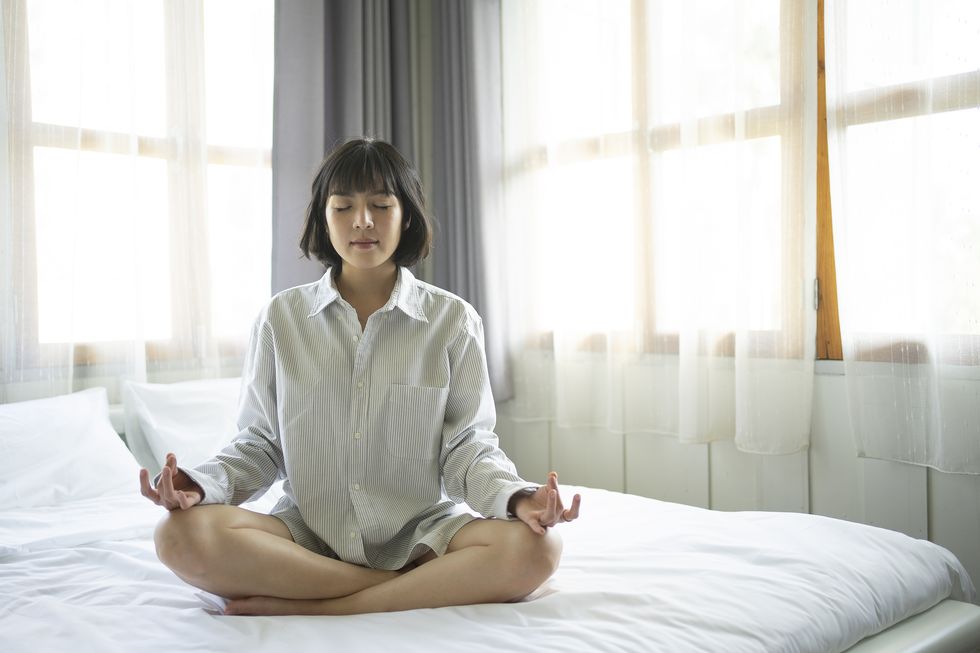 beautiful young female pose and practice meditation on the bed