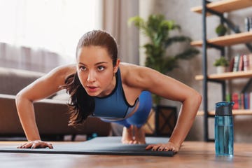 beautiful young sports lady doing push ups while workout at home