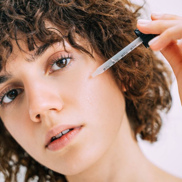 a beautiful young woman applies serum to her face with a pipette close up portrait