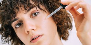 a beautiful young woman applies serum to her face with a pipette close up portrait