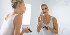 vrouw smeert creme op voor de spiegel