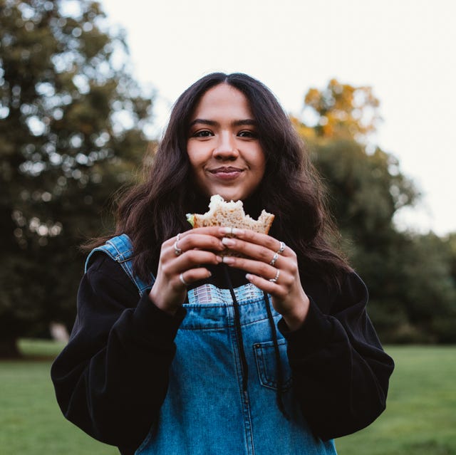 young woman eating a sandwich in a public park