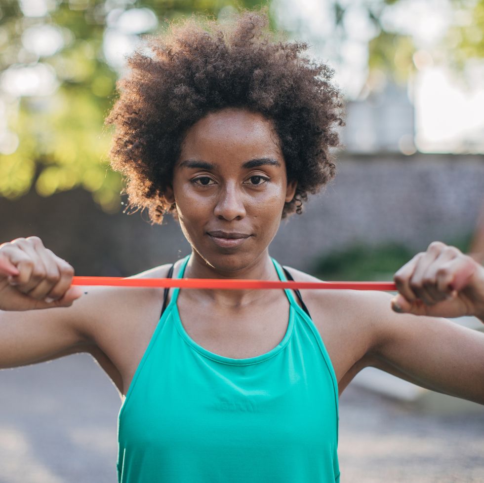 beautiful young black woman exercising in park with a resistance band