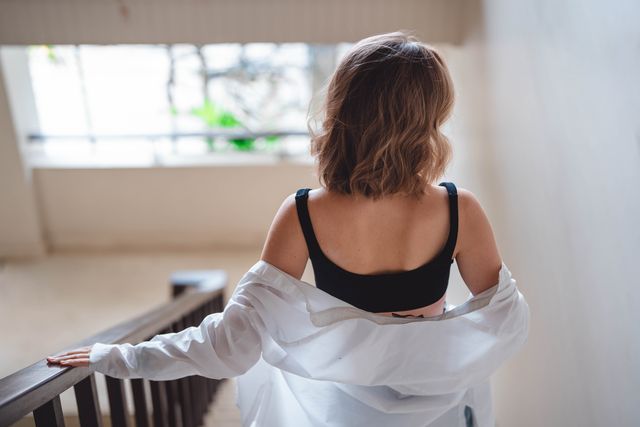 a beautiful young woman in a white shirt comes down the stairs. rear view.