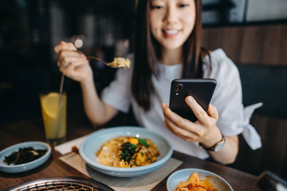 beautiful young woman looking at smartphone while having lunch in a restaurant