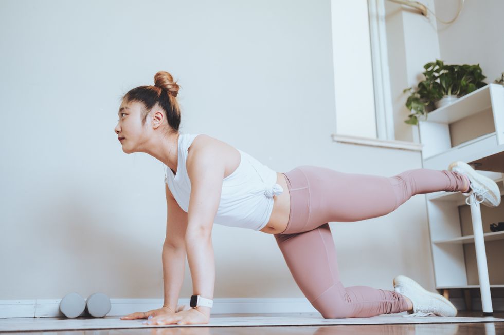 beautiful young woman practicing yoga at home