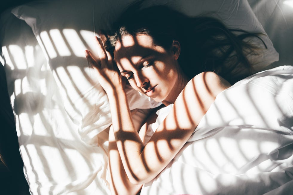 beautiful young woman sleeps in a comfortable bed sunbeam of dawn on her face
