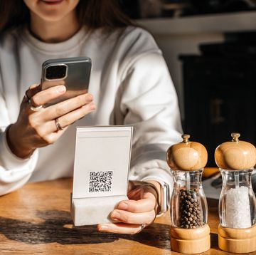 a beautiful young woman with long hair scans a qr code in a café to see the menu online