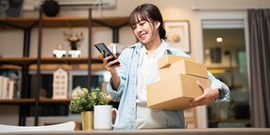 beautiful young woman with smartphone receiving parcel purchased online