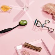 perfume, sunglasses, crystal, sleep mask, eyelash curler and jewelry on pink background