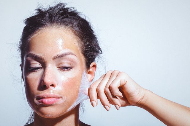 una mujer joven se arranca una mascarilla facial del rostro