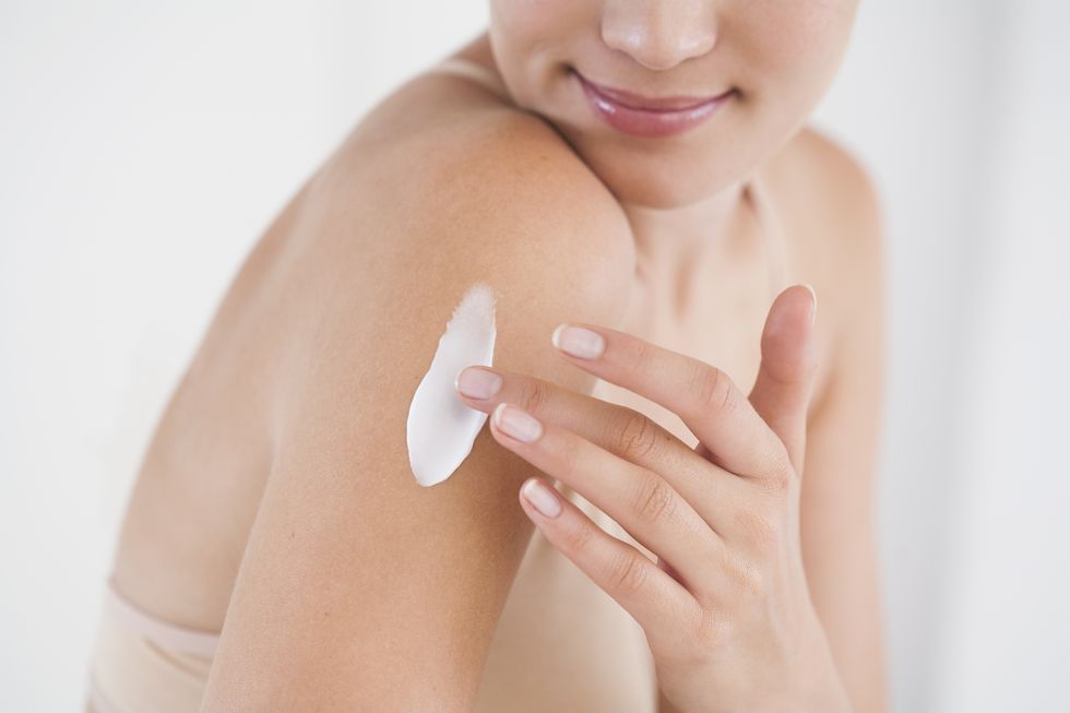 Beauty woman applying cream on arm