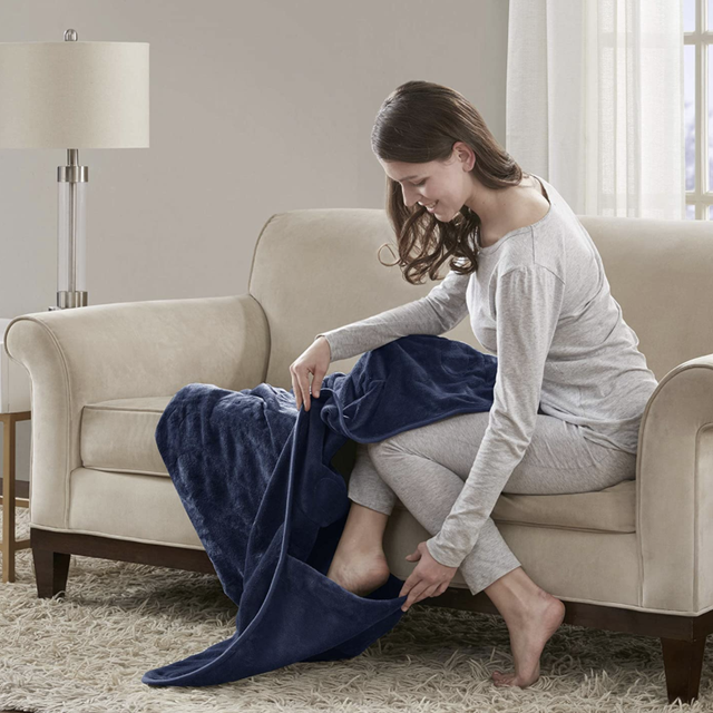 woman putting her feet in the foot pocket of a navy blanket